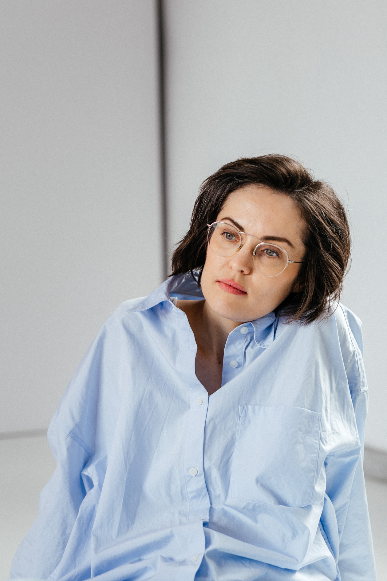 Founder of Embraceme, sitting in a bright room in an oversized light blue shirt